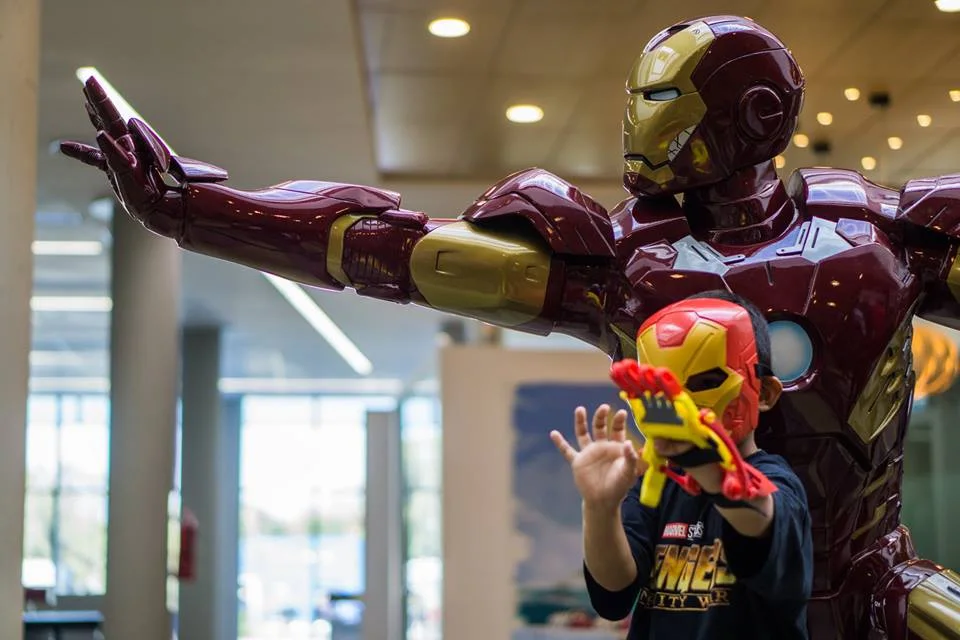 Niño con una prótesis 3D de Atomic Lab junto a una figura de Iron Man