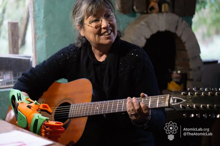 María toca la guitarra usando una prótesis 3D colorida