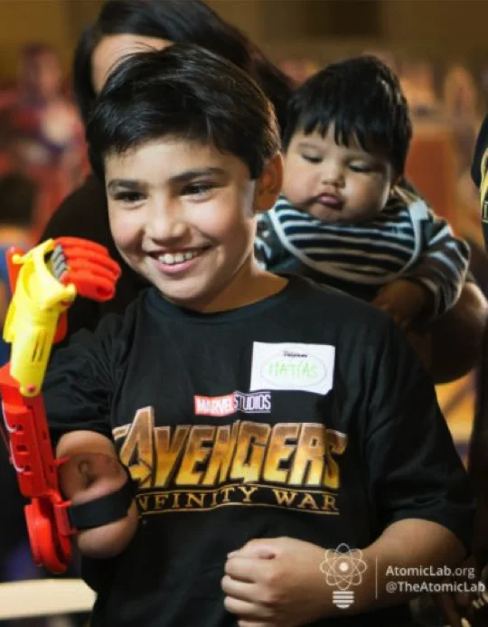 A young person holds a superhero-inspired 3D-printed prosthesis